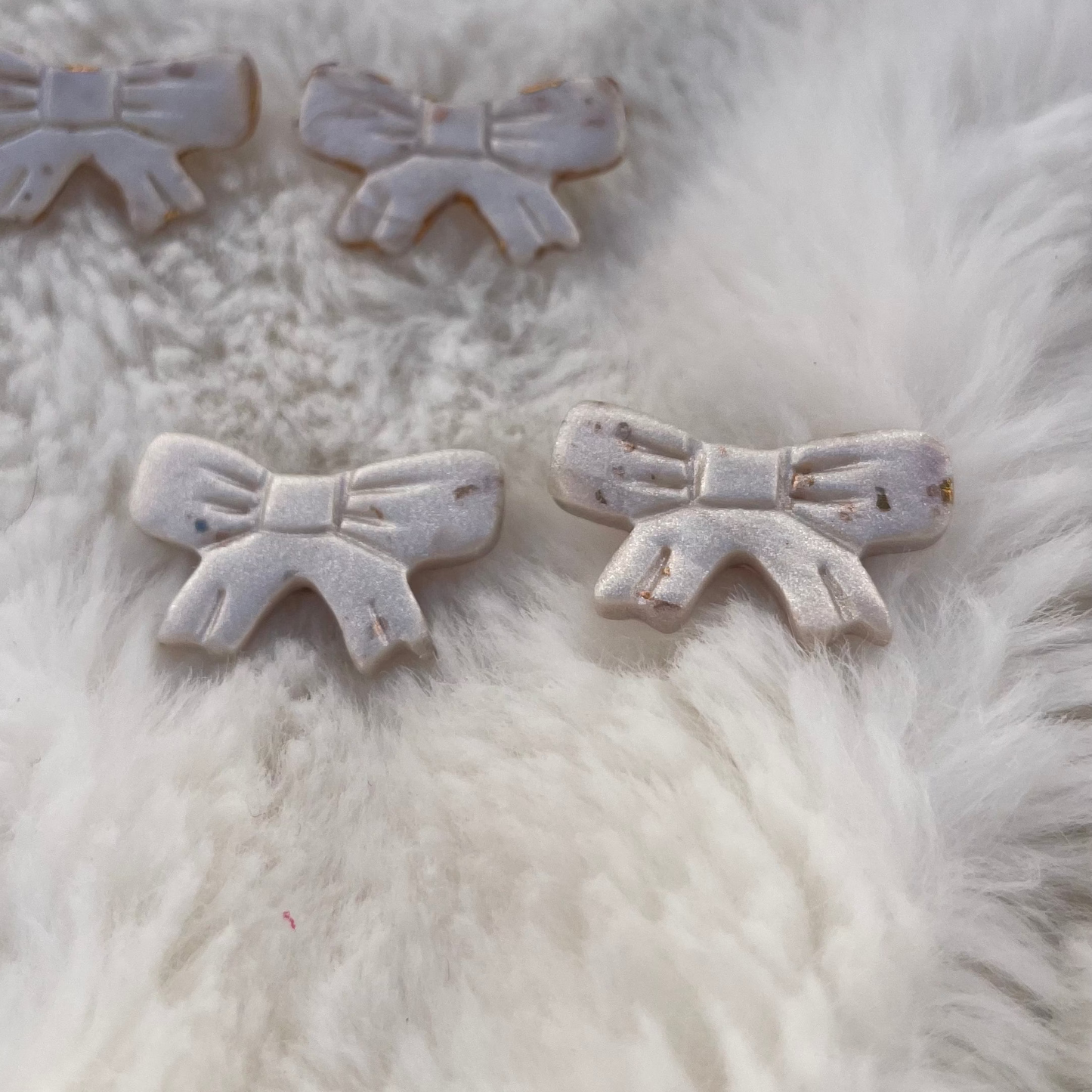 A collection of sparkly pearl bows laid out on a furry surface, showcasing their glittery and elegant appearance.